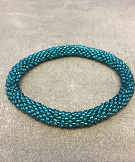 Roll-on armbånd som passer til næsten alle kvinder. Kvindegrupper i Nepal, Kathmandu Valley, udstyres med glasperler og bomuldsgarn, så de i deres fritid kan hækler disse smukke perlearmbånd. Den ekstra indtægt går bl.a. til at sende kvindernes børn i skole. Hvert armbånd er et unikt resultat af kvindernes håndarbejde og varierer i farvekombinationer og mønstre.