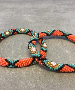 Roll-on armbånd som passer til næsten alle kvinder. Kvindegrupper i Nepal, Kathmandu Valley, udstyres med glasperler og bomuldsgarn, så de i deres fritid kan hækler disse smukke perlearmbånd. Den ekstra indtægt går bl.a. til at sende kvindernes børn i skole. Hvert armbånd er et unikt resultat af kvindernes håndarbejde og varierer i farvekombinationer og mønstre.