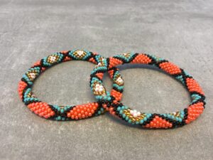 Roll-on armbånd som passer til næsten alle kvinder. Kvindegrupper i Nepal, Kathmandu Valley, udstyres med glasperler og bomuldsgarn, så de i deres fritid kan hækler disse smukke perlearmbånd. Den ekstra indtægt går bl.a. til at sende kvindernes børn i skole. Hvert armbånd er et unikt resultat af kvindernes håndarbejde og varierer i farvekombinationer og mønstre.