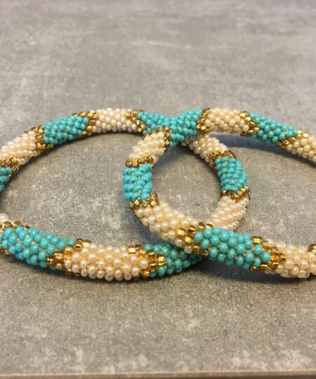 Roll-on armbånd som passer til næsten alle kvinder. Kvindegrupper i Nepal, Kathmandu Valley, udstyres med glasperler og bomuldsgarn, så de i deres fritid kan hækler disse smukke perlearmbånd. Den ekstra indtægt går bl.a. til at sende kvindernes børn i skole. Hvert armbånd er et unikt resultat af kvindernes håndarbejde og varierer i farvekombinationer og mønstre.