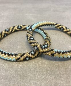 Roll-on armbånd som passer til næsten alle kvinder. Kvindegrupper i Nepal, Kathmandu Valley, udstyres med glasperler og bomuldsgarn, så de i deres fritid kan hækler disse smukke perlearmbånd. Den ekstra indtægt går bl.a. til at sende kvindernes børn i skole. Hvert armbånd er et unikt resultat af kvindernes håndarbejde og varierer i farvekombinationer og mønstre.