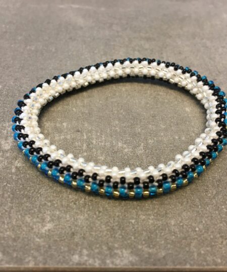 Roll-on armbånd som passer til næsten alle kvinder. Kvindegrupper i Nepal, Kathmandu Valley, udstyres med glasperler og bomuldsgarn, så de i deres fritid kan hækler disse smukke perlearmbånd. Den ekstra indtægt går bl.a. til at sende kvindernes børn i skole. Hvert armbånd er et unikt resultat af kvindernes håndarbejde og varierer i farvekombinationer og mønstre.