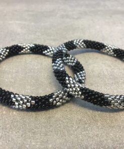 Roll-on armbånd som passer til næsten alle kvinder. Kvindegrupper i Nepal, Kathmandu Valley, udstyres med glasperler og bomuldsgarn, så de i deres fritid kan hækler disse smukke perlearmbånd. Den ekstra indtægt går bl.a. til at sende kvindernes børn i skole. Hvert armbånd er et unikt resultat af kvindernes håndarbejde og varierer i farvekombinationer og mønstre.