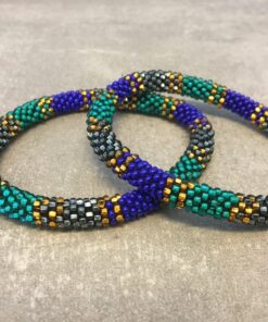 Roll-on armbånd som passer til næsten alle kvinder. Kvindegrupper i Nepal, Kathmandu Valley, udstyres med glasperler og bomuldsgarn, så de i deres fritid kan hækler disse smukke perlearmbånd. Den ekstra indtægt går bl.a. til at sende kvindernes børn i skole. Hvert armbånd er et unikt resultat af kvindernes håndarbejde og varierer i farvekombinationer og mønstre.