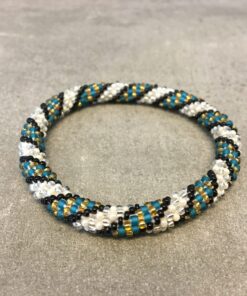 Roll-on armbånd som passer til næsten alle kvinder. Kvindegrupper i Nepal, Kathmandu Valley, udstyres med glasperler og bomuldsgarn, så de i deres fritid kan hækler disse smukke perlearmbånd. Den ekstra indtægt går bl.a. til at sende kvindernes børn i skole. Hvert armbånd er et unikt resultat af kvindernes håndarbejde og varierer i farvekombinationer og mønstre.