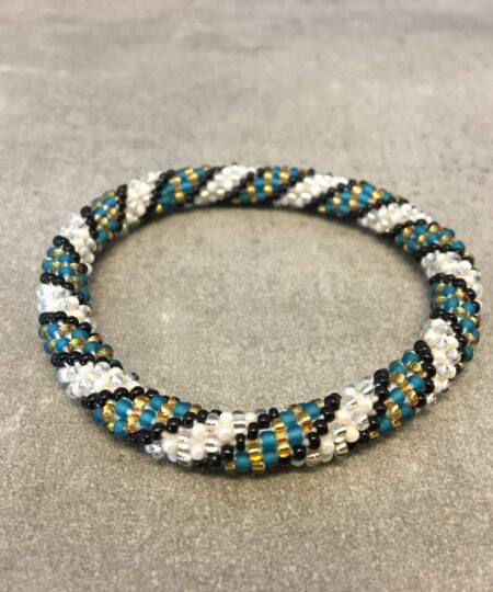 Roll-on armbånd som passer til næsten alle kvinder. Kvindegrupper i Nepal, Kathmandu Valley, udstyres med glasperler og bomuldsgarn, så de i deres fritid kan hækler disse smukke perlearmbånd. Den ekstra indtægt går bl.a. til at sende kvindernes børn i skole. Hvert armbånd er et unikt resultat af kvindernes håndarbejde og varierer i farvekombinationer og mønstre.