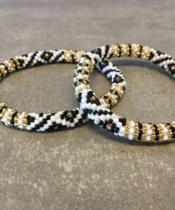 Roll-on armbånd som passer til næsten alle kvinder. Kvindegrupper i Nepal, Kathmandu Valley, udstyres med glasperler og bomuldsgarn, så de i deres fritid kan hækler disse smukke perlearmbånd. Den ekstra indtægt går bl.a. til at sende kvindernes børn i skole. Hvert armbånd er et unikt resultat af kvindernes håndarbejde og varierer i farvekombinationer og mønstre.