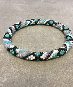 Roll-on armbånd som passer til næsten alle kvinder. Kvindegrupper i Nepal, Kathmandu Valley, udstyres med glasperler og bomuldsgarn, så de i deres fritid kan hækler disse smukke perlearmbånd. Den ekstra indtægt går bl.a. til at sende kvindernes børn i skole. Hvert armbånd er et unikt resultat af kvindernes håndarbejde og varierer i farvekombinationer og mønstre.