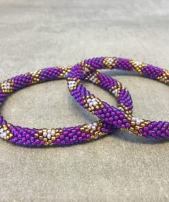 Roll-on armbånd som passer til næsten alle kvinder. Kvindegrupper i Nepal, Kathmandu Valley, udstyres med glasperler og bomuldsgarn, så de i deres fritid kan hækler disse smukke perlearmbånd. Den ekstra indtægt går bl.a. til at sende kvindernes børn i skole. Hvert armbånd er et unikt resultat af kvindernes håndarbejde og varierer i farvekombinationer og mønstre.