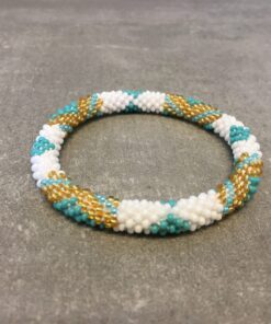 Roll-on armbånd som passer til næsten alle kvinder. Kvindegrupper i Nepal, Kathmandu Valley, udstyres med glasperler og bomuldsgarn, så de i deres fritid kan hækler disse smukke perlearmbånd. Den ekstra indtægt går bl.a. til at sende kvindernes børn i skole. Hvert armbånd er et unikt resultat af kvindernes håndarbejde og varierer i farvekombinationer og mønstre.