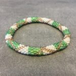 Roll-on armbånd som passer til næsten alle kvinder. Kvindegrupper i Nepal, Kathmandu Valley, udstyres med glasperler og bomuldsgarn, så de i deres fritid kan hækler disse smukke perlearmbånd. Den ekstra indtægt går bl.a. til at sende kvindernes børn i skole. Hvert armbånd er et unikt resultat af kvindernes håndarbejde og varierer i farvekombinationer og mønstre.
