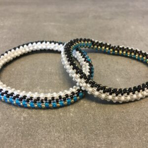 Roll-on armbånd som passer til næsten alle kvinder. Kvindegrupper i Nepal, Kathmandu Valley, udstyres med glasperler og bomuldsgarn, så de i deres fritid kan hækler disse smukke perlearmbånd. Den ekstra indtægt går bl.a. til at sende kvindernes børn i skole. Hvert armbånd er et unikt resultat af kvindernes håndarbejde og varierer i farvekombinationer og mønstre.