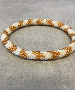 Roll-on armbånd som passer til næsten alle kvinder. Kvindegrupper i Nepal, Kathmandu Valley, udstyres med glasperler og bomuldsgarn, så de i deres fritid kan hækler disse smukke perlearmbånd. Den ekstra indtægt går bl.a. til at sende kvindernes børn i skole. Hvert armbånd er et unikt resultat af kvindernes håndarbejde og varierer i farvekombinationer og mønstre.