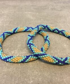 Roll-on armbånd som passer til næsten alle kvinder. Kvindegrupper i Nepal, Kathmandu Valley, udstyres med glasperler og bomuldsgarn, så de i deres fritid kan hækler disse smukke perlearmbånd. Den ekstra indtægt går bl.a. til at sende kvindernes børn i skole. Hvert armbånd er et unikt resultat af kvindernes håndarbejde og varierer i farvekombinationer og mønstre.