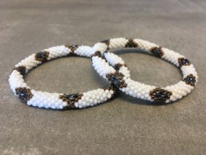 Roll-on armbånd som passer til næsten alle kvinder. Kvindegrupper i Nepal, Kathmandu Valley, udstyres med glasperler og bomuldsgarn, så de i deres fritid kan hækler disse smukke perlearmbånd. Den ekstra indtægt går bl.a. til at sende kvindernes børn i skole. Hvert armbånd er et unikt resultat af kvindernes håndarbejde og varierer i farvekombinationer og mønstre.