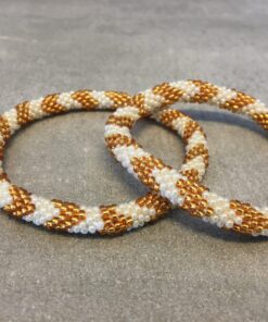 Roll-on armbånd som passer til næsten alle kvinder. Kvindegrupper i Nepal, Kathmandu Valley, udstyres med glasperler og bomuldsgarn, så de i deres fritid kan hækler disse smukke perlearmbånd. Den ekstra indtægt går bl.a. til at sende kvindernes børn i skole. Hvert armbånd er et unikt resultat af kvindernes håndarbejde og varierer i farvekombinationer og mønstre.