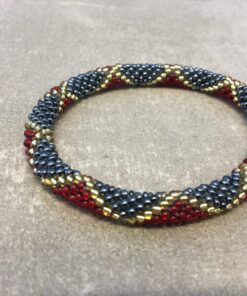 Roll-on armbånd som passer til næsten alle kvinder. Kvindegrupper i Nepal, Kathmandu Valley, udstyres med glasperler og bomuldsgarn, så de i deres fritid kan hækler disse smukke perlearmbånd. Den ekstra indtægt går bl.a. til at sende kvindernes børn i skole. Hvert armbånd er et unikt resultat af kvindernes håndarbejde og varierer i farvekombinationer og mønstre.