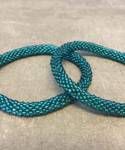 Roll-on armbånd som passer til næsten alle kvinder. Kvindegrupper i Nepal, Kathmandu Valley, udstyres med glasperler og bomuldsgarn, så de i deres fritid kan hækler disse smukke perlearmbånd. Den ekstra indtægt går bl.a. til at sende kvindernes børn i skole. Hvert armbånd er et unikt resultat af kvindernes håndarbejde og varierer i farvekombinationer og mønstre.