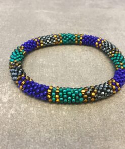 Roll-on armbånd som passer til næsten alle kvinder. Kvindegrupper i Nepal, Kathmandu Valley, udstyres med glasperler og bomuldsgarn, så de i deres fritid kan hækler disse smukke perlearmbånd. Den ekstra indtægt går bl.a. til at sende kvindernes børn i skole. Hvert armbånd er et unikt resultat af kvindernes håndarbejde og varierer i farvekombinationer og mønstre.