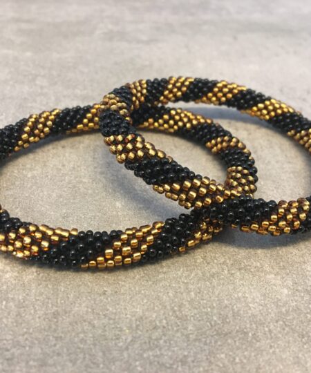 Roll-on armbånd som passer til næsten alle kvinder. Kvindegrupper i Nepal, Kathmandu Valley, udstyres med glasperler og bomuldsgarn, så de i deres fritid kan hækler disse smukke perlearmbånd. Den ekstra indtægt går bl.a. til at sende kvindernes børn i skole. Hvert armbånd er et unikt resultat af kvindernes håndarbejde og varierer i farvekombinationer og mønstre.