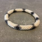 Roll-on armbånd som passer til næsten alle kvinder. Kvindegrupper i Nepal, Kathmandu Valley, udstyres med glasperler og bomuldsgarn, så de i deres fritid kan hækler disse smukke perlearmbånd. Den ekstra indtægt går bl.a. til at sende kvindernes børn i skole. Hvert armbånd er et unikt resultat af kvindernes håndarbejde og varierer i farvekombinationer og mønstre.