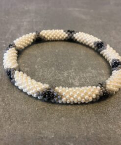 Roll-on armbånd som passer til næsten alle kvinder. Kvindegrupper i Nepal, Kathmandu Valley, udstyres med glasperler og bomuldsgarn, så de i deres fritid kan hækler disse smukke perlearmbånd. Den ekstra indtægt går bl.a. til at sende kvindernes børn i skole. Hvert armbånd er et unikt resultat af kvindernes håndarbejde og varierer i farvekombinationer og mønstre.