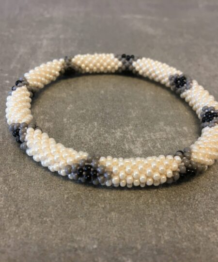 Roll-on armbånd som passer til næsten alle kvinder. Kvindegrupper i Nepal, Kathmandu Valley, udstyres med glasperler og bomuldsgarn, så de i deres fritid kan hækler disse smukke perlearmbånd. Den ekstra indtægt går bl.a. til at sende kvindernes børn i skole. Hvert armbånd er et unikt resultat af kvindernes håndarbejde og varierer i farvekombinationer og mønstre.