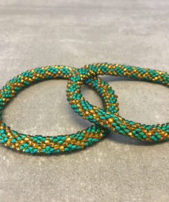 Roll-on armbånd som passer til næsten alle kvinder. Kvindegrupper i Nepal, Kathmandu Valley, udstyres med glasperler og bomuldsgarn, så de i deres fritid kan hækler disse smukke perlearmbånd. Den ekstra indtægt går bl.a. til at sende kvindernes børn i skole. Hvert armbånd er et unikt resultat af kvindernes håndarbejde og varierer i farvekombinationer og mønstre.