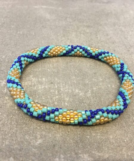 Roll-on armbånd som passer til næsten alle kvinder. Kvindegrupper i Nepal, Kathmandu Valley, udstyres med glasperler og bomuldsgarn, så de i deres fritid kan hækler disse smukke perlearmbånd. Den ekstra indtægt går bl.a. til at sende kvindernes børn i skole. Hvert armbånd er et unikt resultat af kvindernes håndarbejde og varierer i farvekombinationer og mønstre.