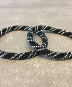 Roll-on armbånd som passer til næsten alle kvinder. Kvindegrupper i Nepal, Kathmandu Valley, udstyres med glasperler og bomuldsgarn, så de i deres fritid kan hækler disse smukke perlearmbånd. Den ekstra indtægt går bl.a. til at sende kvindernes børn i skole. Hvert armbånd er et unikt resultat af kvindernes håndarbejde og varierer i farvekombinationer og mønstre.