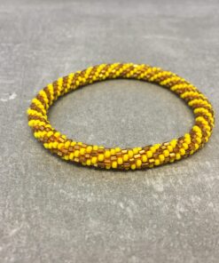 Roll-on armbånd som passer til næsten alle kvinder. Kvindegrupper i Nepal, Kathmandu Valley, udstyres med glasperler og bomuldsgarn, så de i deres fritid kan hækler disse smukke perlearmbånd. Den ekstra indtægt går bl.a. til at sende kvindernes børn i skole. Hvert armbånd er et unikt resultat af kvindernes håndarbejde og varierer i farvekombinationer og mønstre.