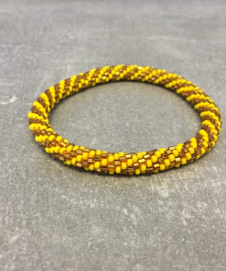 Roll-on armbånd som passer til næsten alle kvinder. Kvindegrupper i Nepal, Kathmandu Valley, udstyres med glasperler og bomuldsgarn, så de i deres fritid kan hækler disse smukke perlearmbånd. Den ekstra indtægt går bl.a. til at sende kvindernes børn i skole. Hvert armbånd er et unikt resultat af kvindernes håndarbejde og varierer i farvekombinationer og mønstre.