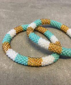 Roll-on armbånd som passer til næsten alle kvinder. Kvindegrupper i Nepal, Kathmandu Valley, udstyres med glasperler og bomuldsgarn, så de i deres fritid kan hækler disse smukke perlearmbånd. Den ekstra indtægt går bl.a. til at sende kvindernes børn i skole. Hvert armbånd er et unikt resultat af kvindernes håndarbejde og varierer i farvekombinationer og mønstre.