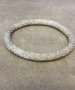 Roll-on armbånd som passer til næsten alle kvinder. Kvindegrupper i Nepal, Kathmandu Valley, udstyres med glasperler og bomuldsgarn, så de i deres fritid kan hækler disse smukke perlearmbånd. Den ekstra indtægt går bl.a. til at sende kvindernes børn i skole. Hvert armbånd er et unikt resultat af kvindernes håndarbejde og varierer i farvekombinationer og mønstre.