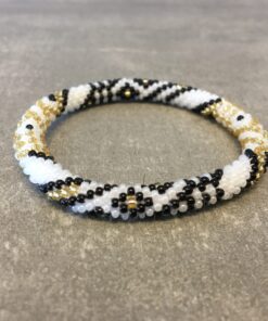 Roll-on armbånd som passer til næsten alle kvinder. Kvindegrupper i Nepal, Kathmandu Valley, udstyres med glasperler og bomuldsgarn, så de i deres fritid kan hækler disse smukke perlearmbånd. Den ekstra indtægt går bl.a. til at sende kvindernes børn i skole. Hvert armbånd er et unikt resultat af kvindernes håndarbejde og varierer i farvekombinationer og mønstre.