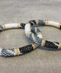 Roll-on armbånd som passer til næsten alle kvinder. Kvindegrupper i Nepal, Kathmandu Valley, udstyres med glasperler og bomuldsgarn, så de i deres fritid kan hækler disse smukke perlearmbånd. Den ekstra indtægt går bl.a. til at sende kvindernes børn i skole. Hvert armbånd er et unikt resultat af kvindernes håndarbejde og varierer i farvekombinationer og mønstre.