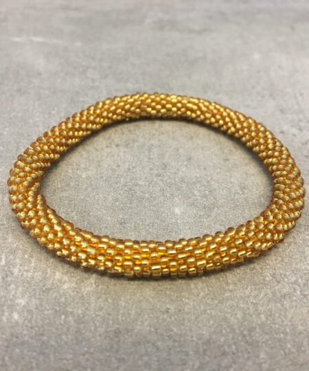 Roll-on armbånd som passer til næsten alle kvinder. Kvindegrupper i Nepal, Kathmandu Valley, udstyres med glasperler og bomuldsgarn, så de i deres fritid kan hækler disse smukke perlearmbånd. Den ekstra indtægt går bl.a. til at sende kvindernes børn i skole. Hvert armbånd er et unikt resultat af kvindernes håndarbejde og varierer i farvekombinationer og mønstre.