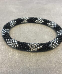 Roll-on armbånd som passer til næsten alle kvinder. Kvindegrupper i Nepal, Kathmandu Valley, udstyres med glasperler og bomuldsgarn, så de i deres fritid kan hækler disse smukke perlearmbånd. Den ekstra indtægt går bl.a. til at sende kvindernes børn i skole. Hvert armbånd er et unikt resultat af kvindernes håndarbejde og varierer i farvekombinationer og mønstre.