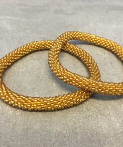 Roll-on armbånd som passer til næsten alle kvinder. Kvindegrupper i Nepal, Kathmandu Valley, udstyres med glasperler og bomuldsgarn, så de i deres fritid kan hækler disse smukke perlearmbånd. Den ekstra indtægt går bl.a. til at sende kvindernes børn i skole. Hvert armbånd er et unikt resultat af kvindernes håndarbejde og varierer i farvekombinationer og mønstre.