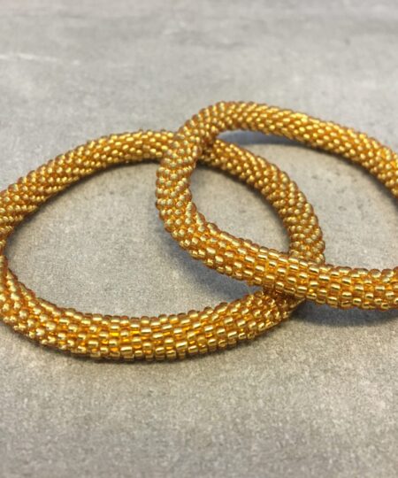 Roll-on armbånd som passer til næsten alle kvinder. Kvindegrupper i Nepal, Kathmandu Valley, udstyres med glasperler og bomuldsgarn, så de i deres fritid kan hækler disse smukke perlearmbånd. Den ekstra indtægt går bl.a. til at sende kvindernes børn i skole. Hvert armbånd er et unikt resultat af kvindernes håndarbejde og varierer i farvekombinationer og mønstre.