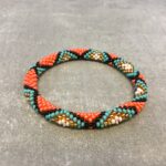 Roll-on armbånd som passer til næsten alle kvinder. Kvindegrupper i Nepal, Kathmandu Valley, udstyres med glasperler og bomuldsgarn, så de i deres fritid kan hækler disse smukke perlearmbånd. Den ekstra indtægt går bl.a. til at sende kvindernes børn i skole. Hvert armbånd er et unikt resultat af kvindernes håndarbejde og varierer i farvekombinationer og mønstre.