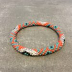 Roll-on armbånd som passer til næsten alle kvinder. Kvindegrupper i Nepal, Kathmandu Valley, udstyres med glasperler og bomuldsgarn, så de i deres fritid kan hækler disse smukke perlearmbånd. Den ekstra indtægt går bl.a. til at sende kvindernes børn i skole. Hvert armbånd er et unikt resultat af kvindernes håndarbejde og varierer i farvekombinationer og mønstre.