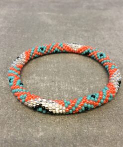 Roll-on armbånd som passer til næsten alle kvinder. Kvindegrupper i Nepal, Kathmandu Valley, udstyres med glasperler og bomuldsgarn, så de i deres fritid kan hækler disse smukke perlearmbånd. Den ekstra indtægt går bl.a. til at sende kvindernes børn i skole. Hvert armbånd er et unikt resultat af kvindernes håndarbejde og varierer i farvekombinationer og mønstre.