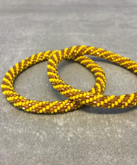 Roll-on armbånd som passer til næsten alle kvinder. Kvindegrupper i Nepal, Kathmandu Valley, udstyres med glasperler og bomuldsgarn, så de i deres fritid kan hækler disse smukke perlearmbånd. Den ekstra indtægt går bl.a. til at sende kvindernes børn i skole. Hvert armbånd er et unikt resultat af kvindernes håndarbejde og varierer i farvekombinationer og mønstre.