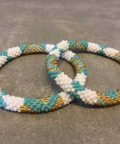 Roll-on armbånd som passer til næsten alle kvinder. Kvindegrupper i Nepal, Kathmandu Valley, udstyres med glasperler og bomuldsgarn, så de i deres fritid kan hækler disse smukke perlearmbånd. Den ekstra indtægt går bl.a. til at sende kvindernes børn i skole. Hvert armbånd er et unikt resultat af kvindernes håndarbejde og varierer i farvekombinationer og mønstre.