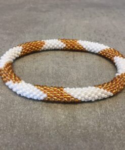 Roll-on armbånd som passer til næsten alle kvinder. Kvindegrupper i Nepal, Kathmandu Valley, udstyres med glasperler og bomuldsgarn, så de i deres fritid kan hækler disse smukke perlearmbånd. Den ekstra indtægt går bl.a. til at sende kvindernes børn i skole. Hvert armbånd er et unikt resultat af kvindernes håndarbejde og varierer i farvekombinationer og mønstre.