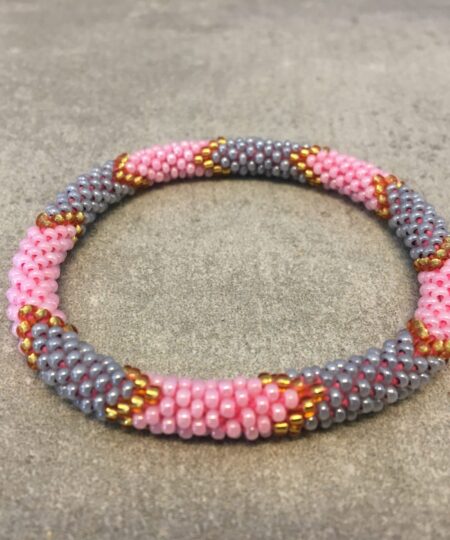 Roll-on armbånd som passer til næsten alle kvinder. Kvindegrupper i Nepal, Kathmandu Valley, udstyres med glasperler og bomuldsgarn, så de i deres fritid kan hækler disse smukke perlearmbånd. Den ekstra indtægt går bl.a. til at sende kvindernes børn i skole. Hvert armbånd er et unikt resultat af kvindernes håndarbejde og varierer i farvekombinationer og mønstre.