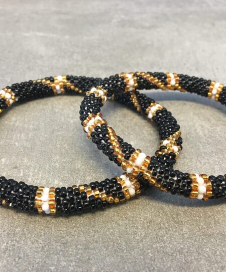 Roll-on armbånd som passer til næsten alle kvinder. Kvindegrupper i Nepal, Kathmandu Valley, udstyres med glasperler og bomuldsgarn, så de i deres fritid kan hækler disse smukke perlearmbånd. Den ekstra indtægt går bl.a. til at sende kvindernes børn i skole. Hvert armbånd er et unikt resultat af kvindernes håndarbejde og varierer i farvekombinationer og mønstre.