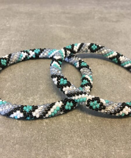 Roll-on armbånd som passer til næsten alle kvinder. Kvindegrupper i Nepal, Kathmandu Valley, udstyres med glasperler og bomuldsgarn, så de i deres fritid kan hækler disse smukke perlearmbånd. Den ekstra indtægt går bl.a. til at sende kvindernes børn i skole. Hvert armbånd er et unikt resultat af kvindernes håndarbejde og varierer i farvekombinationer og mønstre.