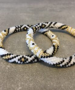 Roll-on armbånd som passer til næsten alle kvinder. Kvindegrupper i Nepal, Kathmandu Valley, udstyres med glasperler og bomuldsgarn, så de i deres fritid kan hækler disse smukke perlearmbånd. Den ekstra indtægt går bl.a. til at sende kvindernes børn i skole. Hvert armbånd er et unikt resultat af kvindernes håndarbejde og varierer i farvekombinationer og mønstre.